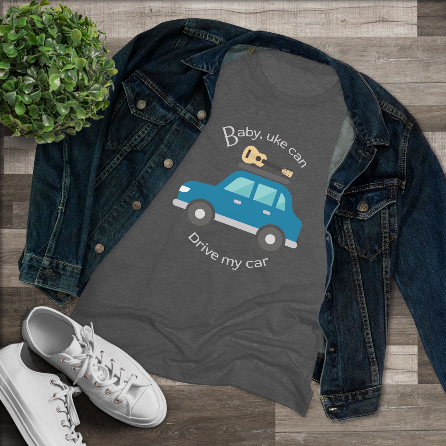 Heathered black t-shirt with ‘Baby, uke can drive my car’ and a graphic of a car with a ukulele on the roof printed on it, styled with a denim jacket and white sneakers.