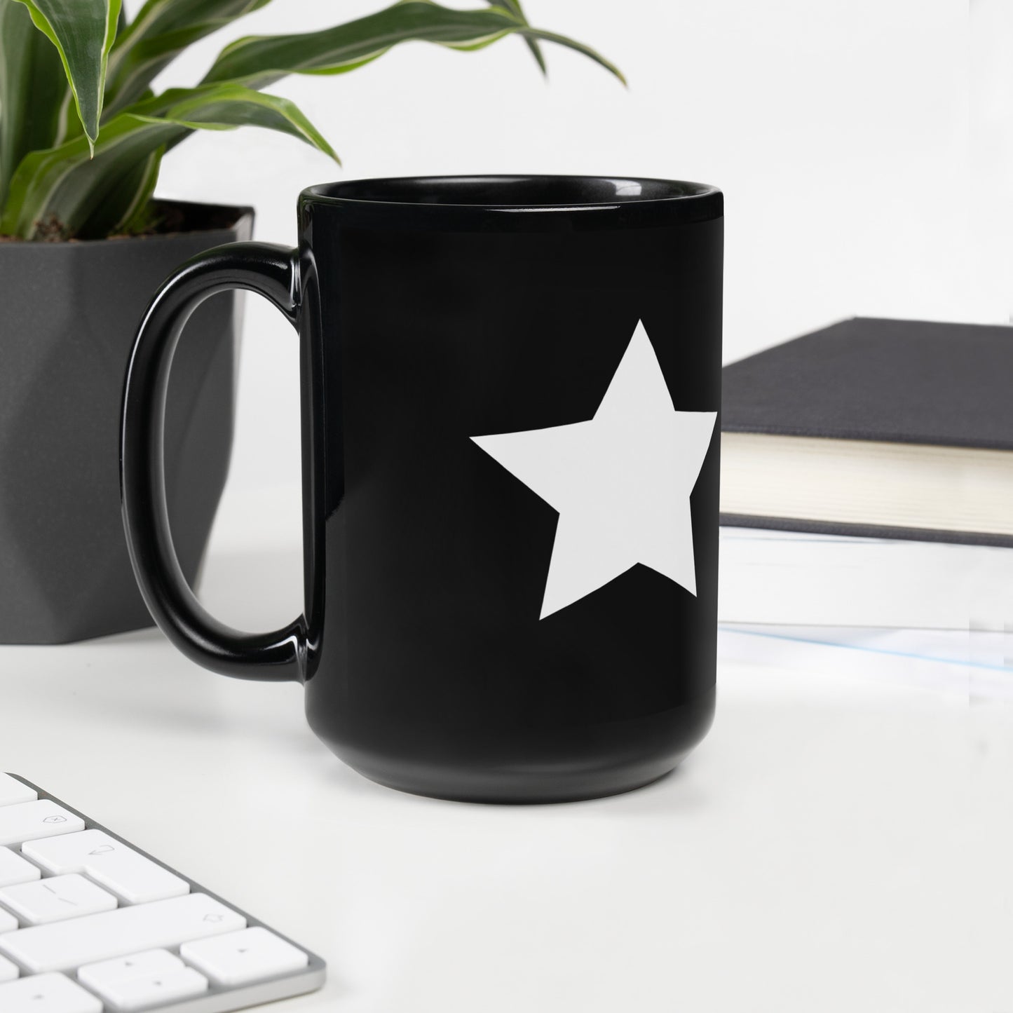 A glossy black mug with a white star printed on the right side of the handle.