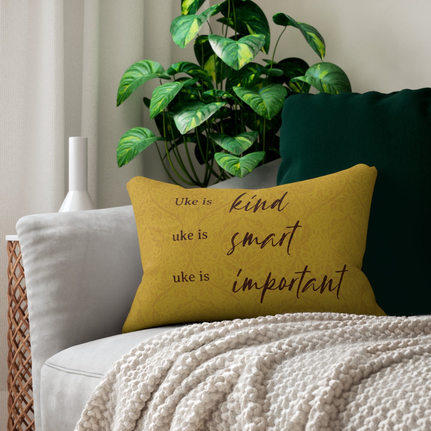 A throw pillow with a mustard-colored patterned background and 'Uke is kind, uke is smart, uke is important' printed on it, sitting on a sofa.