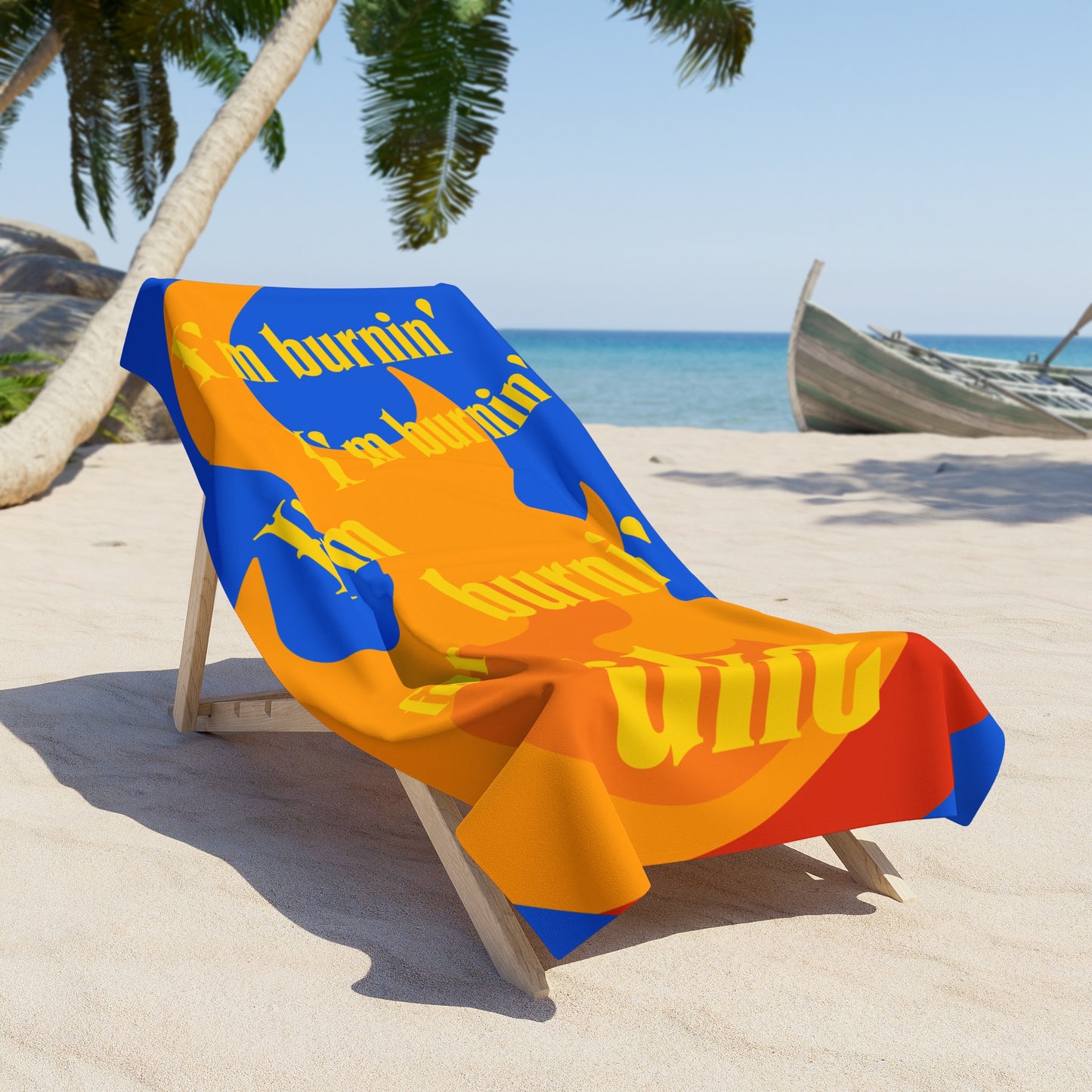 Beach towel draped over a chair, printed with a flame background and the text 'I'm burnin', I'm burnin', I'm burnin' for uke.'