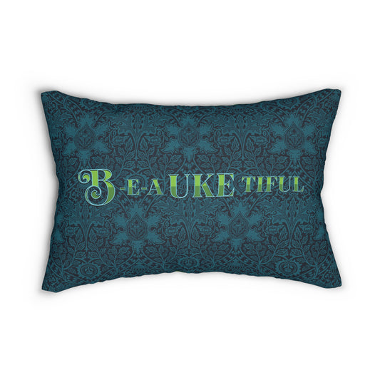 A throw pillow with a dark teal patterned background and 'B-E-A-UKE-tiful' in bold green letters printed on it.