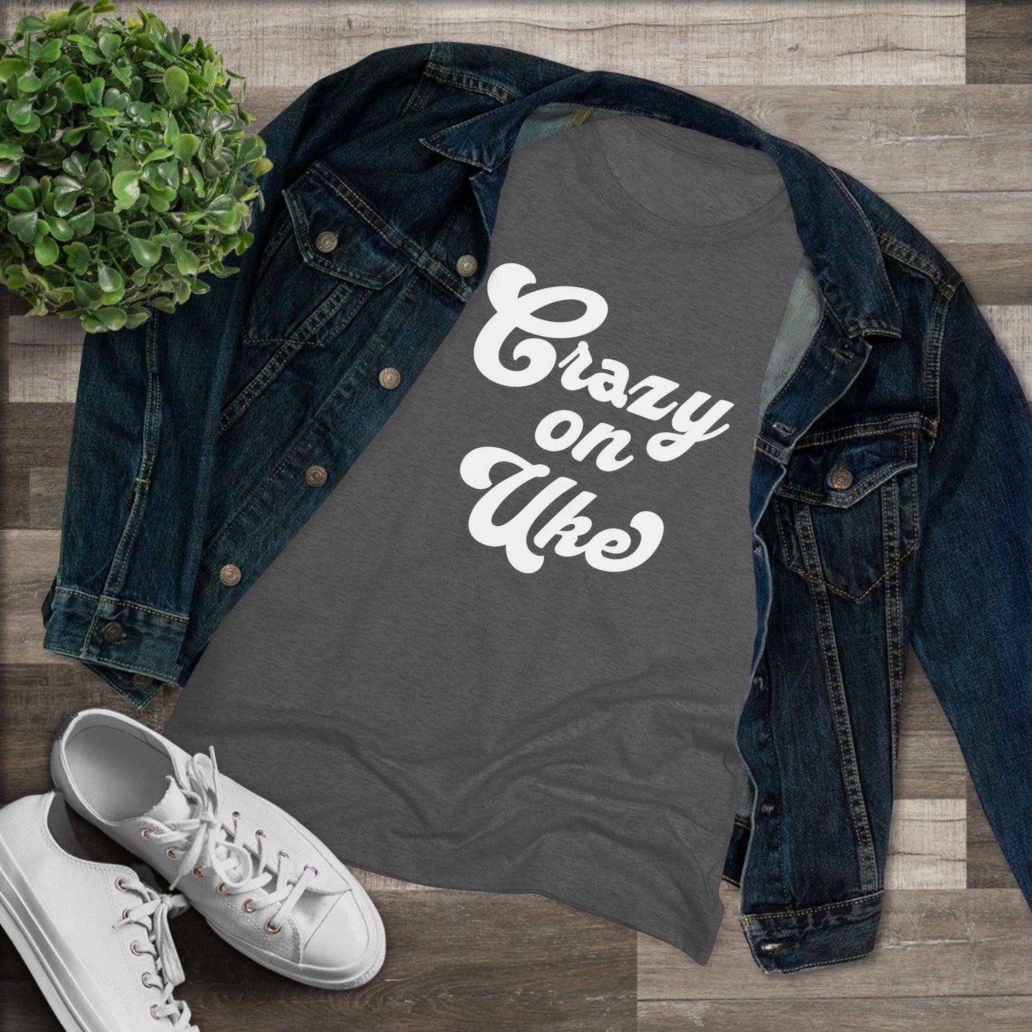 Heathered black t-shirt with 'Crazy On Uke' in white cursive text printed on it, styled with a denim jacket and white sneakers.