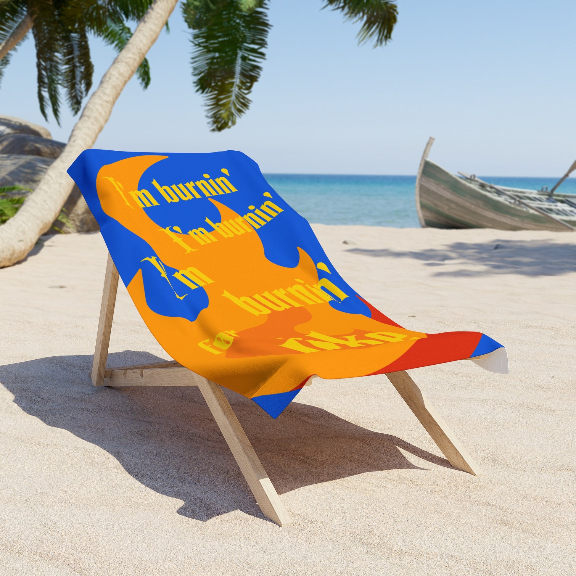 Beach towel draped over a chair, printed with a flame background and the text 'I'm burnin', I'm burnin', I'm burnin' for uke.'
