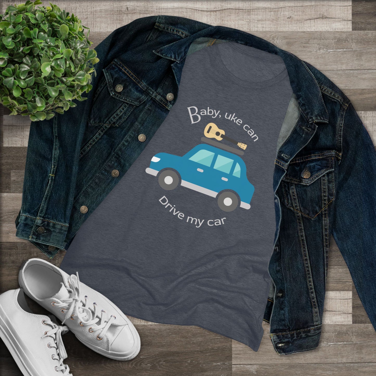 Heathered navy t-shirt with ‘Baby, uke can drive my car’ and a graphic of a car with a ukulele on the roof printed on it, styled with a denim jacket and white sneakers.