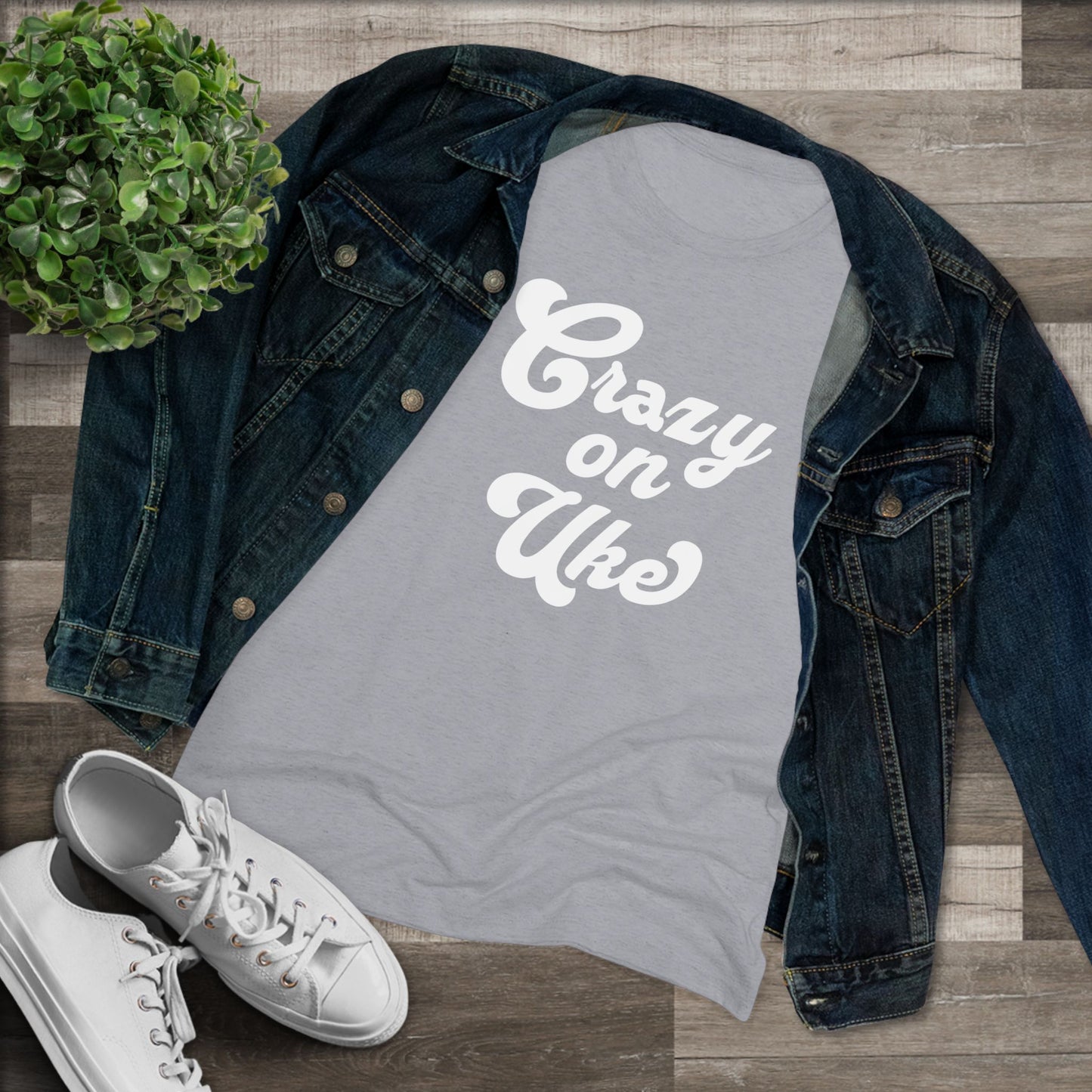 Grey t-shirt with 'Crazy On Uke' in white cursive text printed on it, styled with a denim jacket and white sneakers.