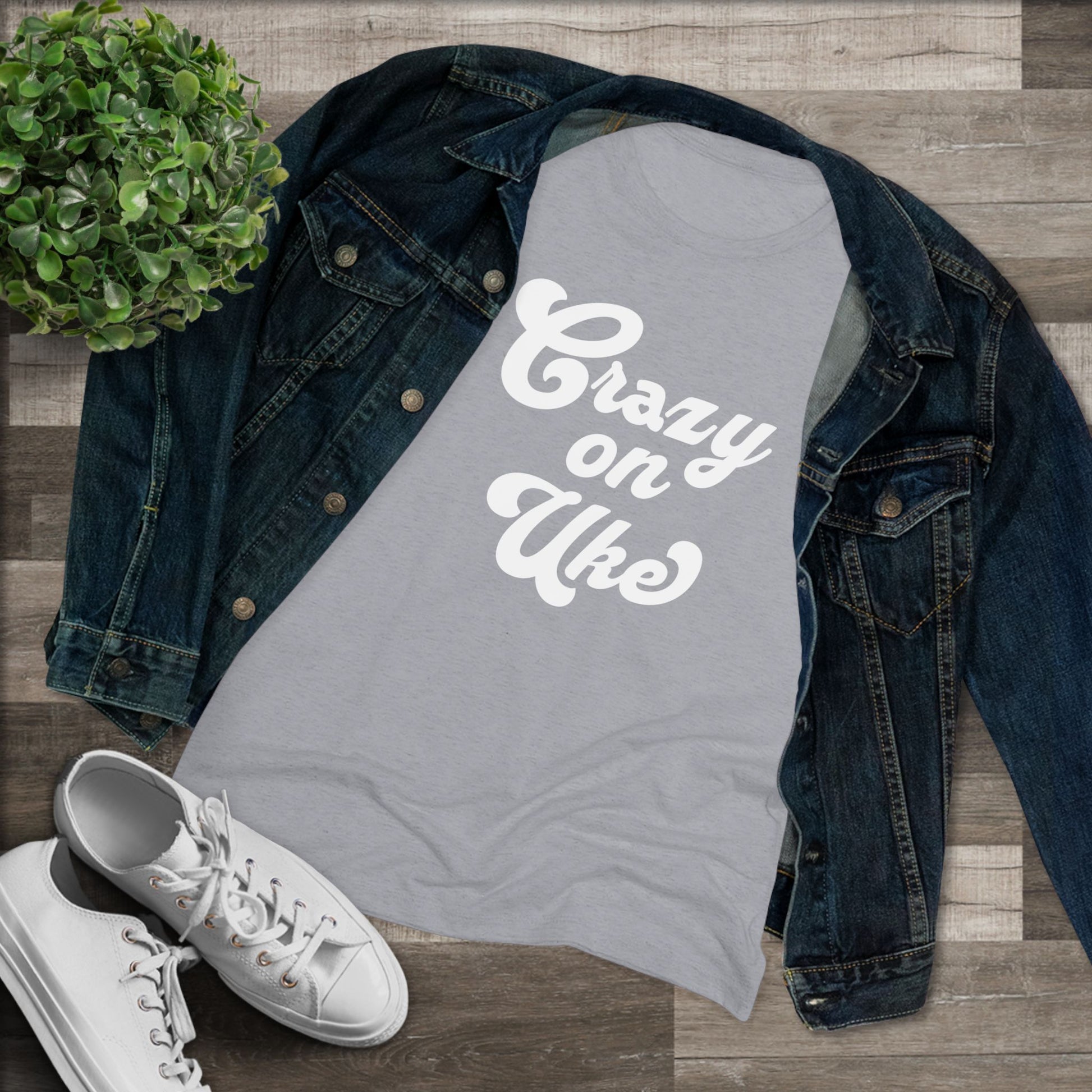 Grey t-shirt with 'Crazy On Uke' in white cursive text printed on it, styled with a denim jacket and white sneakers.