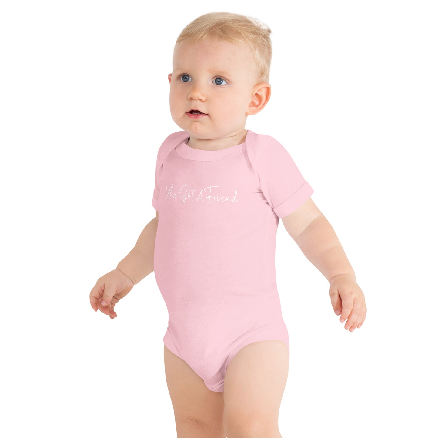 A baby wearing a light pink onesie printed with 'Uke Got A Friend' in white cursive text.