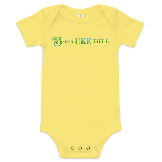 Yellow baby onesie with ‘B-E-A-UKE-tiful’ printed in green block letters with a decorative letter B.