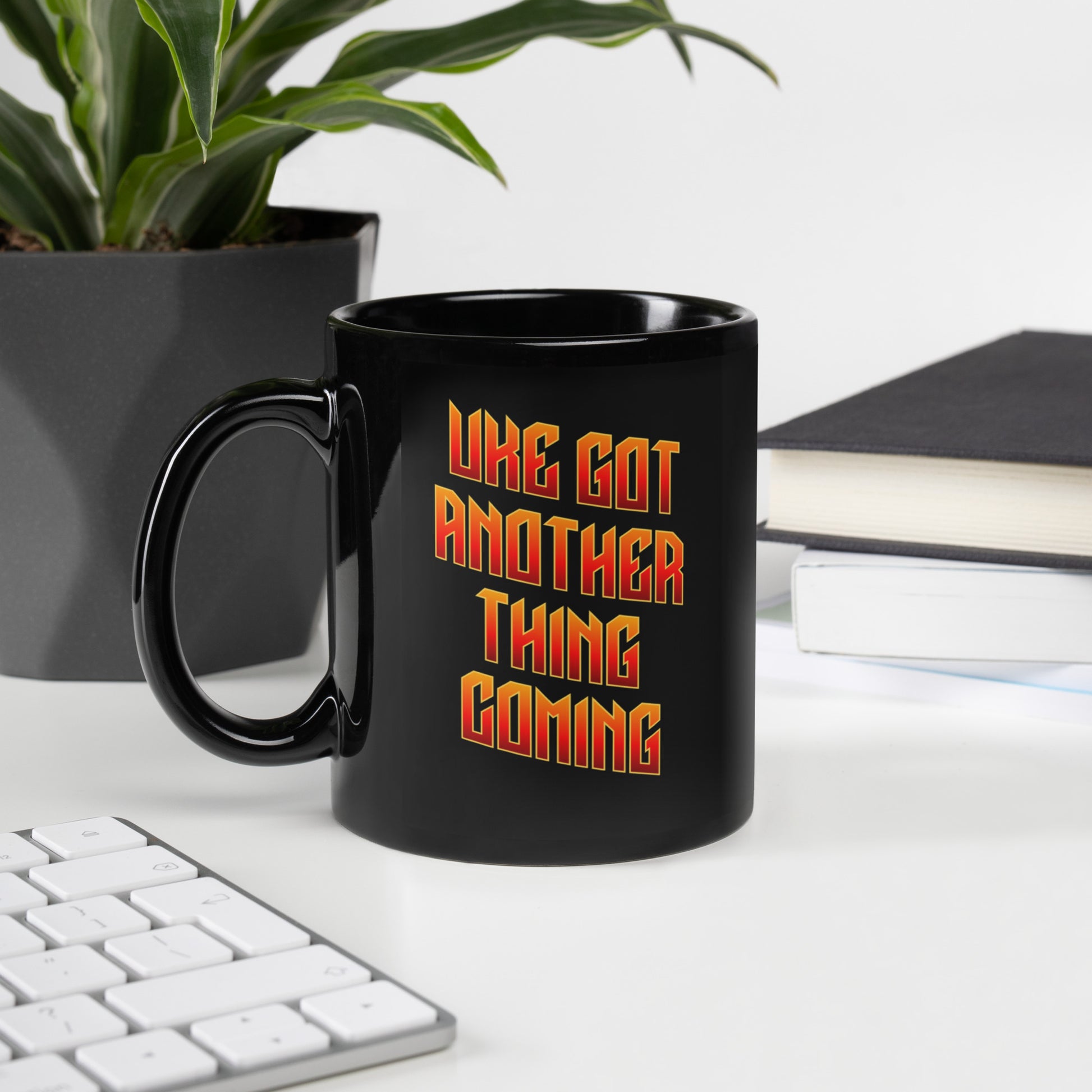 Glossy black mug with ‘Uke Got Another Thing Coming' in orange and yellow slanted block letters printed on the side to the right of the handle.