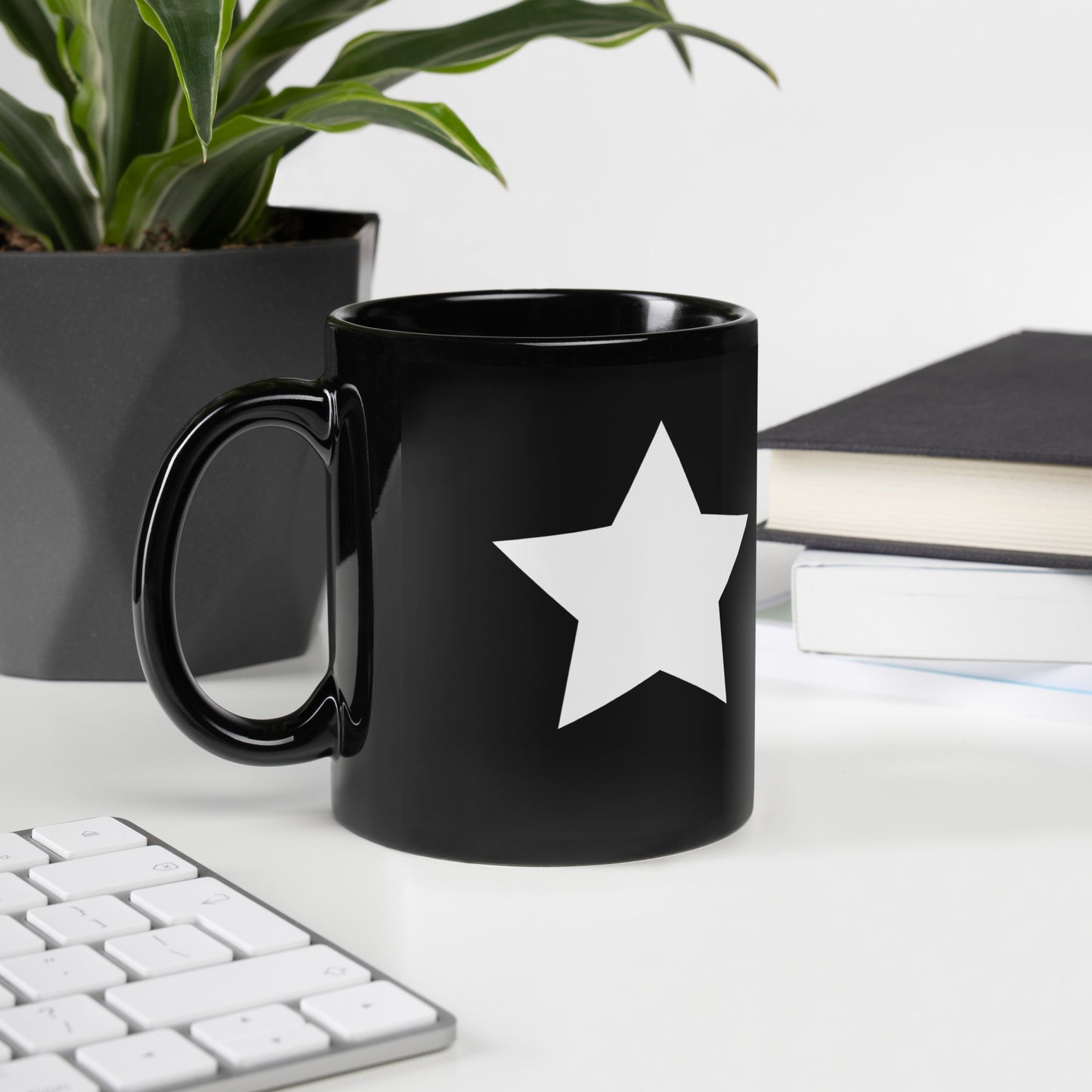 A glossy black mug with a white star printed on the side to the right of the mug handle.