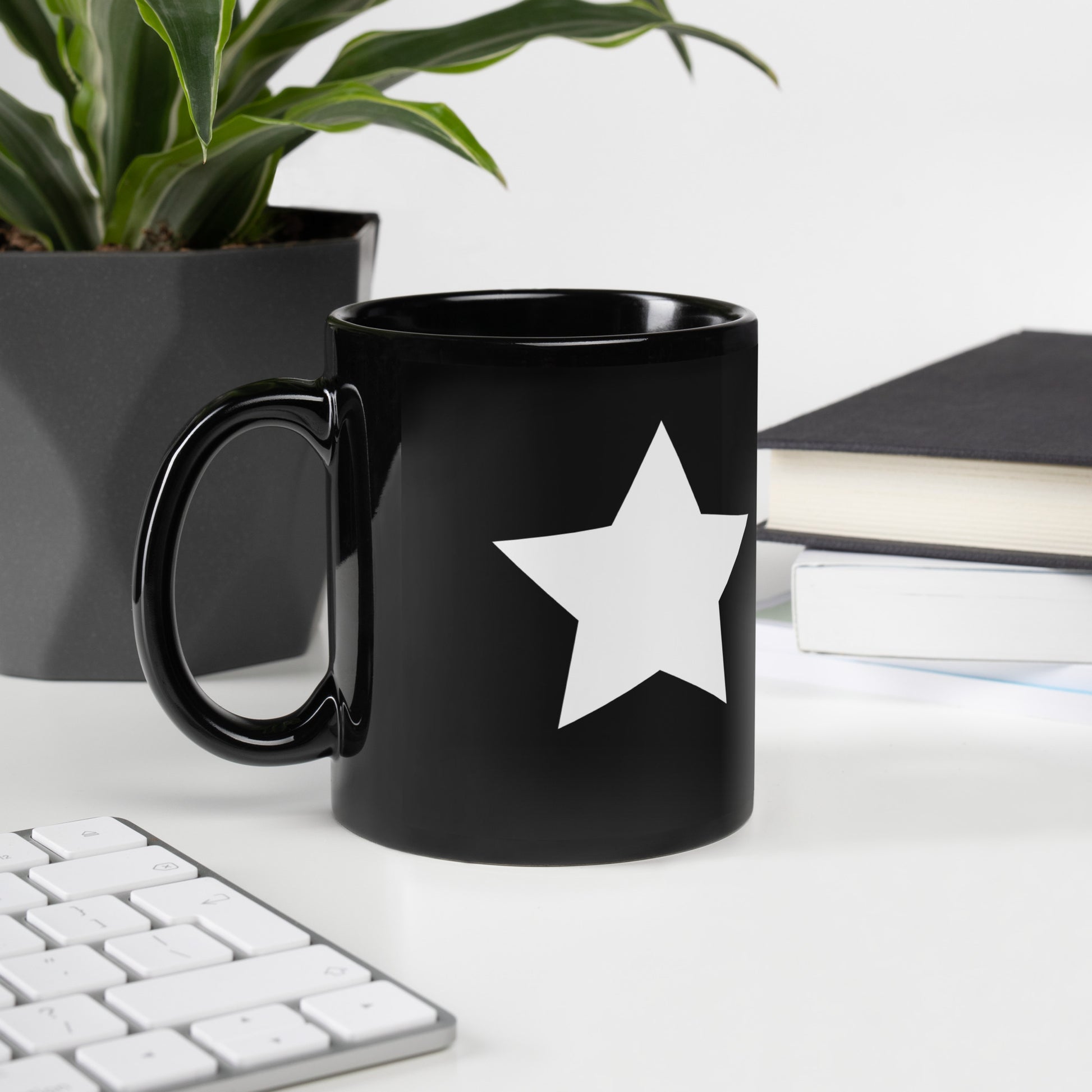 A glossy black mug with a white star printed on the side to the right of the mug handle.
