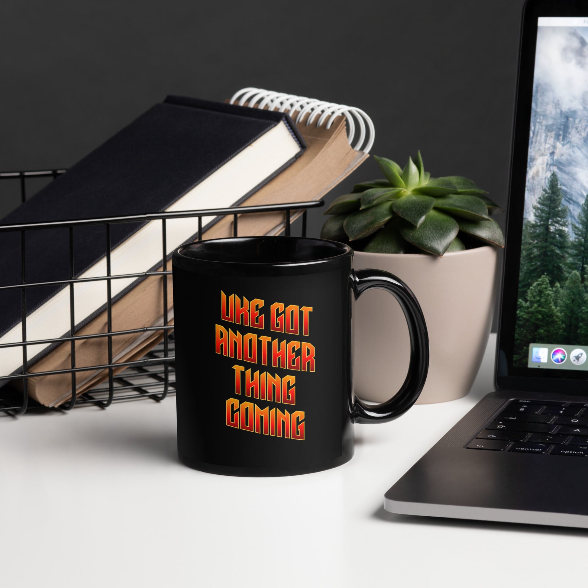 Glossy black mug with ‘Uke Got Another Thing Coming' in orange and yellow slanted block letters printed on the side to the left of the handle.