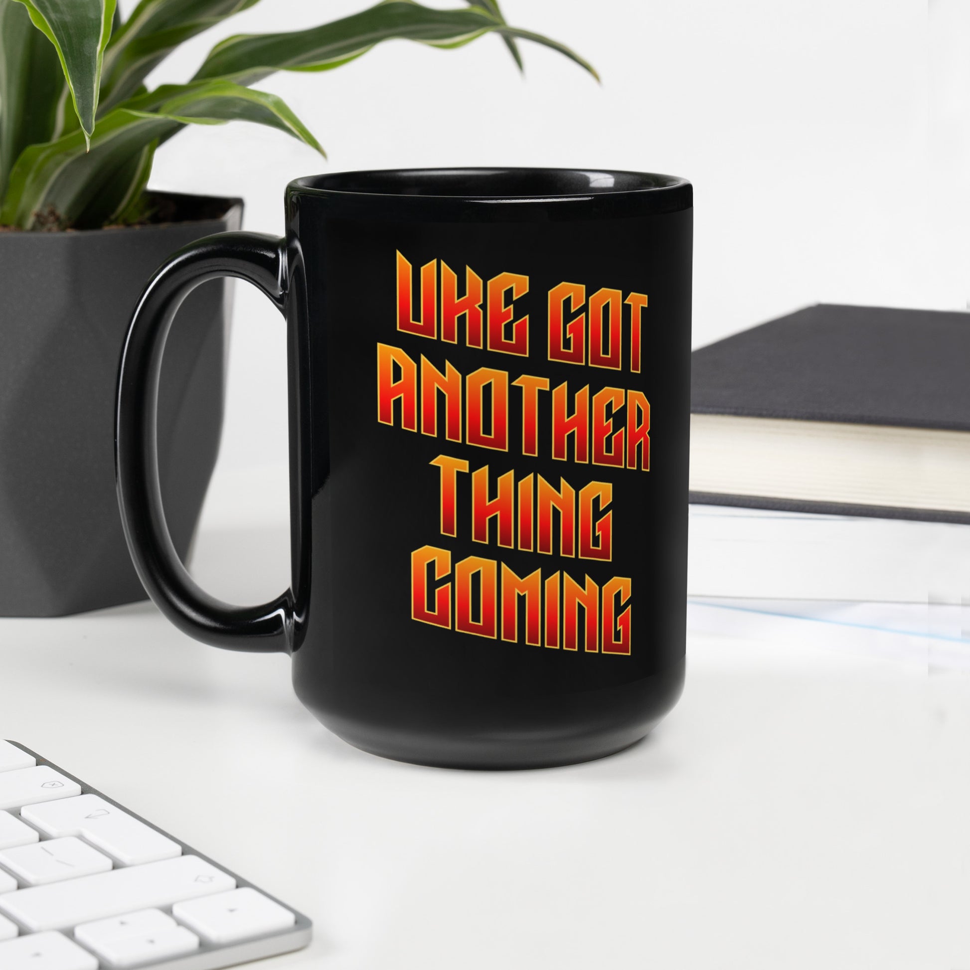 15-ounce glossy black mug with ‘Uke Got Another Thing Coming' in orange and yellow slanted block letters printed on the side to the right of the handle.