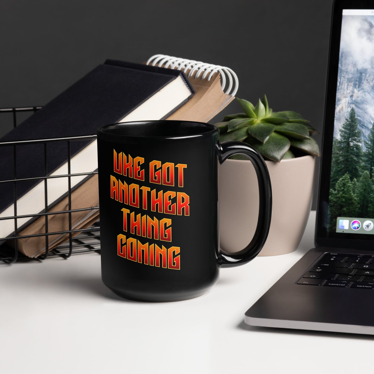 15-ounce glossy black mug with ‘Uke Got Another Thing Coming' in orange and yellow slanted block letters printed on the side to the left of the handle.