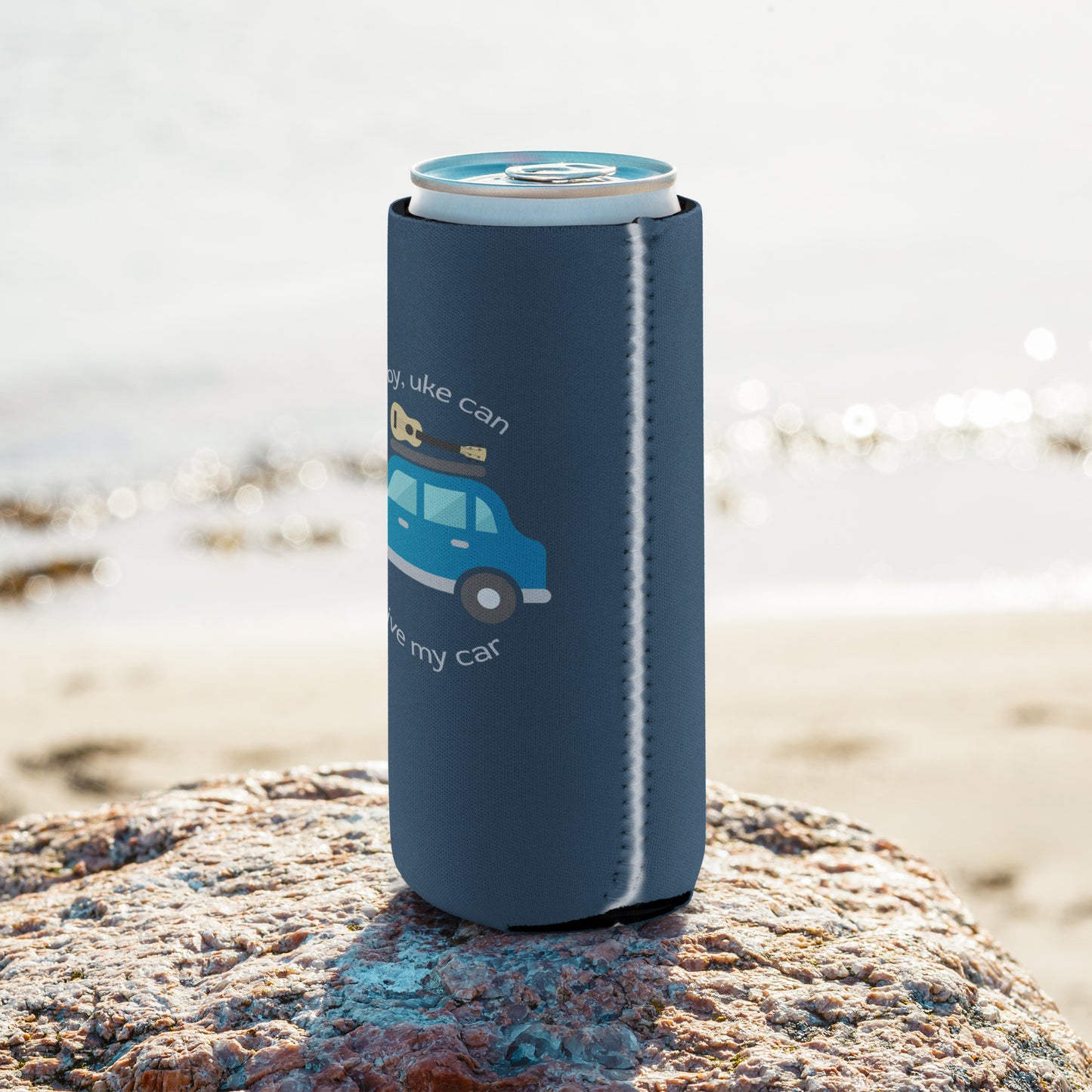 Slim can coozie printed with an indigo background and ‘Baby, uke can drive my car’ with a graphic of a car with a ukulele on the roof.