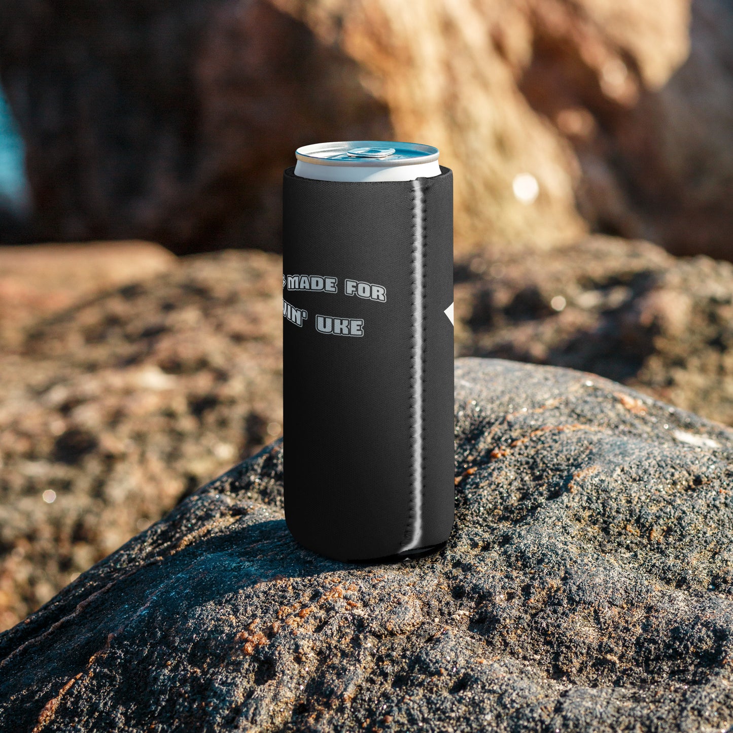 The side of a slim can coozie with a black background and 'I was made for lovin' uke' printed in black and white block letters, with a glimpse of the white star on the backside.