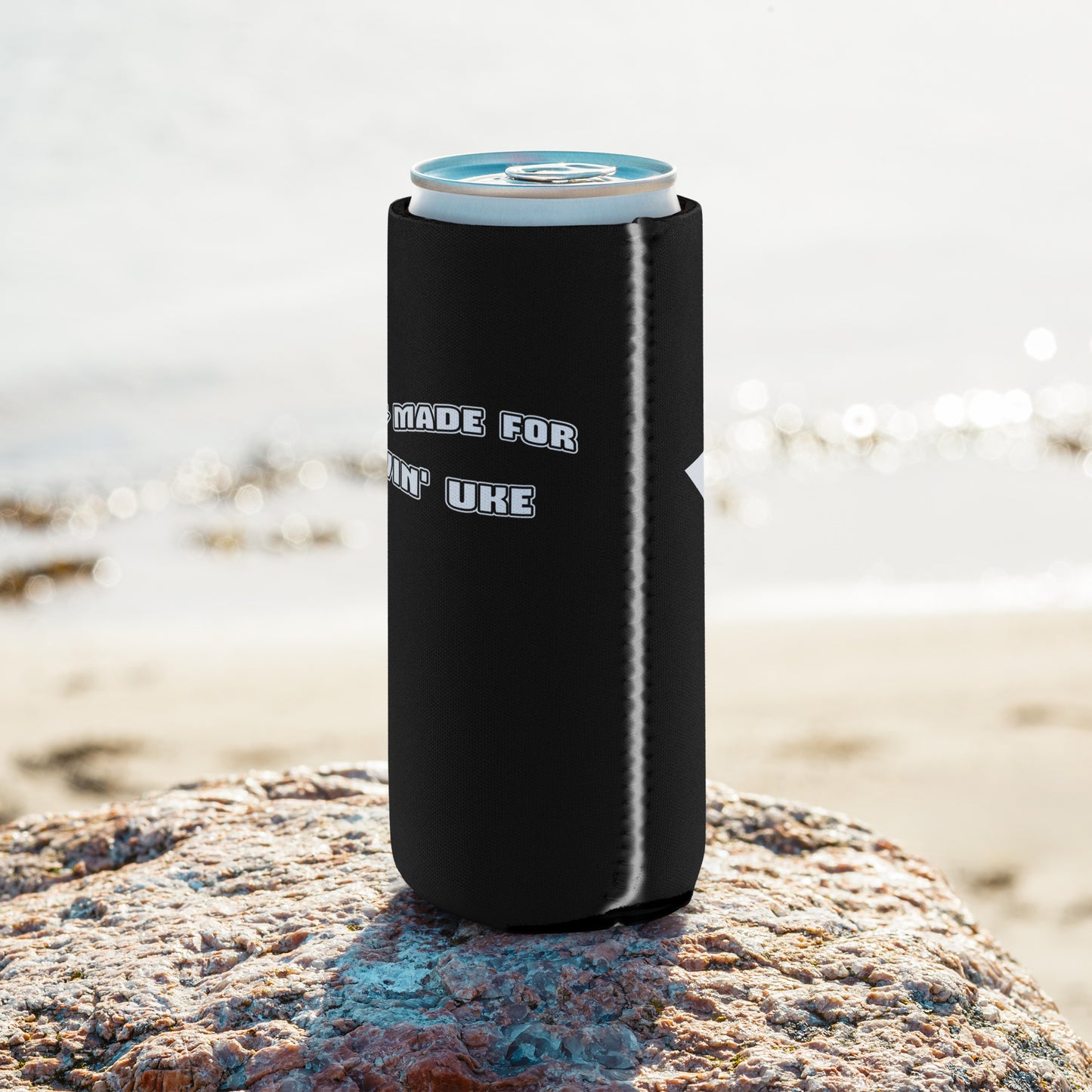 The side of a regular-sized can coozie with a black background and 'I was made for lovin' uke' printed in black and white block letters, with a glimpse of the white star on the backside.