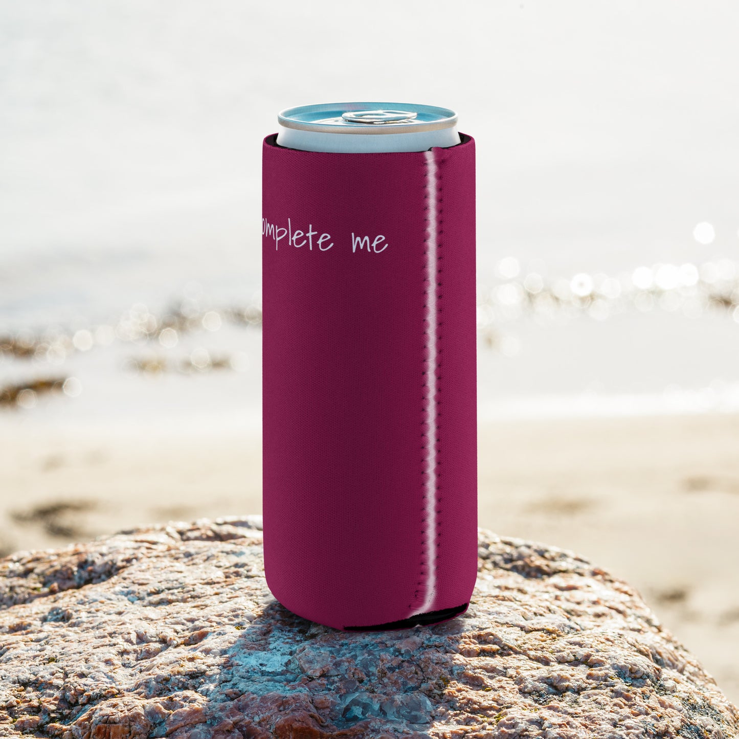 A slim can coozie printed with a maroon background and the words 'Uke Complete Me' in white lowercase text.