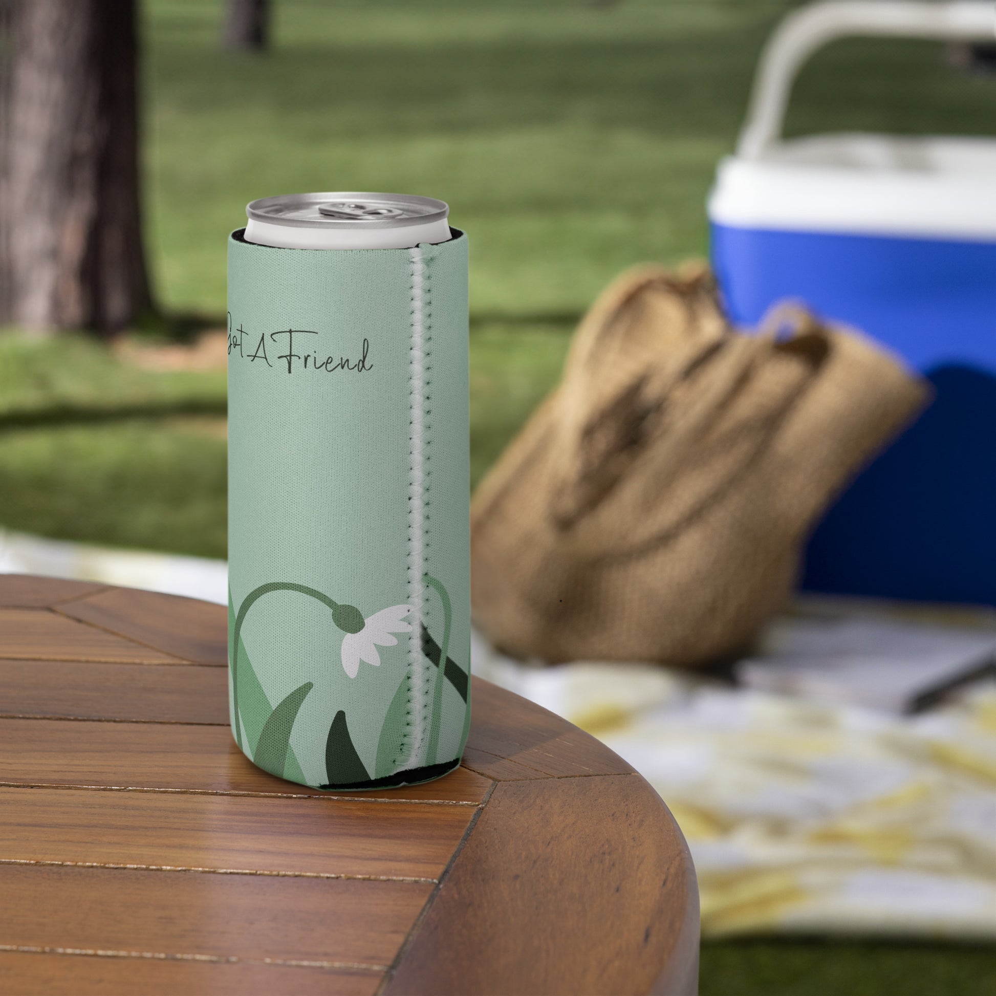 A slim can coozie with a flower design on a green background and the words 'Uke Got A Friend' printed on it.
