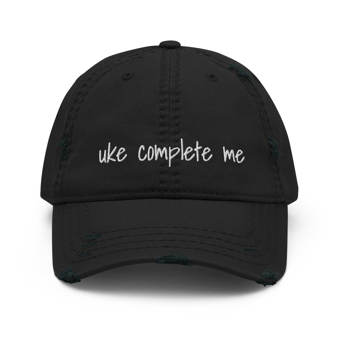 Black baseball cap with a distressed look and 'Uke complete me' embroidered on it with white thread.
