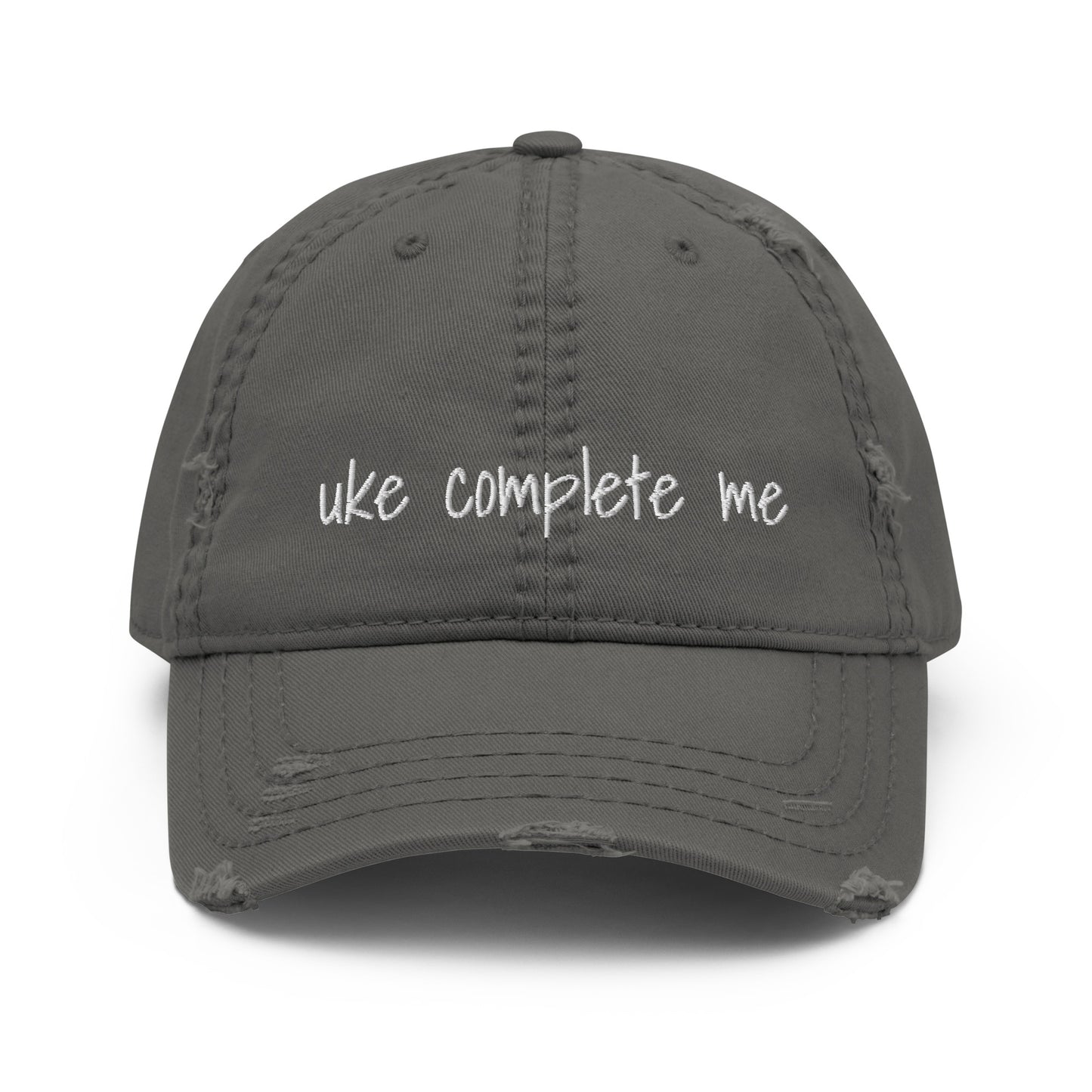 Grey baseball cap with a distressed look and 'Uke complete me' embroidered on it with white thread.