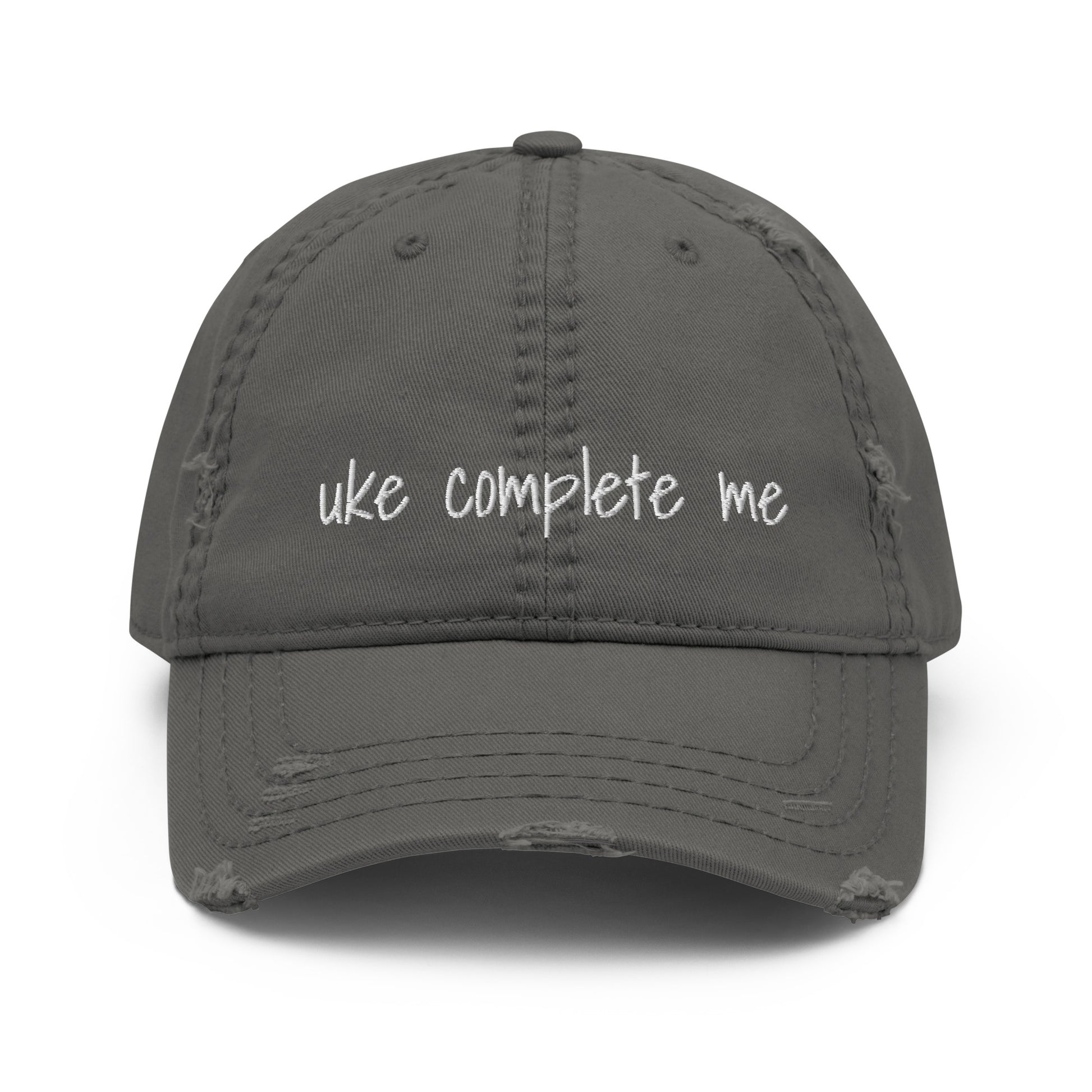 Grey baseball cap with a distressed look and 'Uke complete me' embroidered on it with white thread.