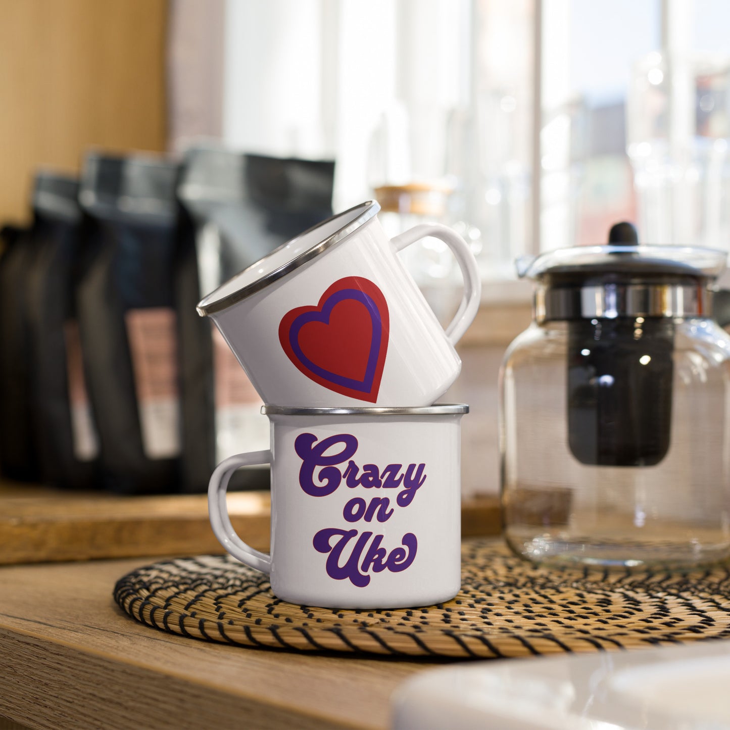 A stack of two white enamel mugs showing what both sides of a single mug look like. One side has a red and purple heart and the other side has red and purple bold cursive letters that say 'Crazy On Uke.’
