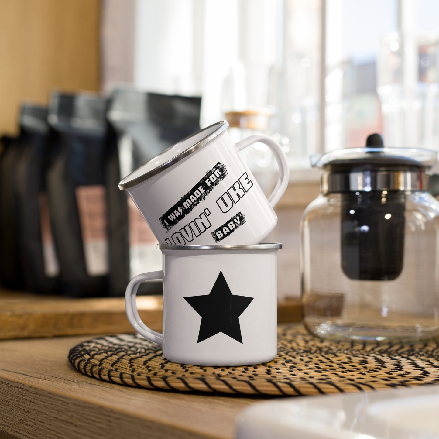 A stack of two white enamel mugs showing what both sides of a single mug look like. One side has a black star and the other side has black and white block letters that say 'I was made for lovin' uke, Baby.'