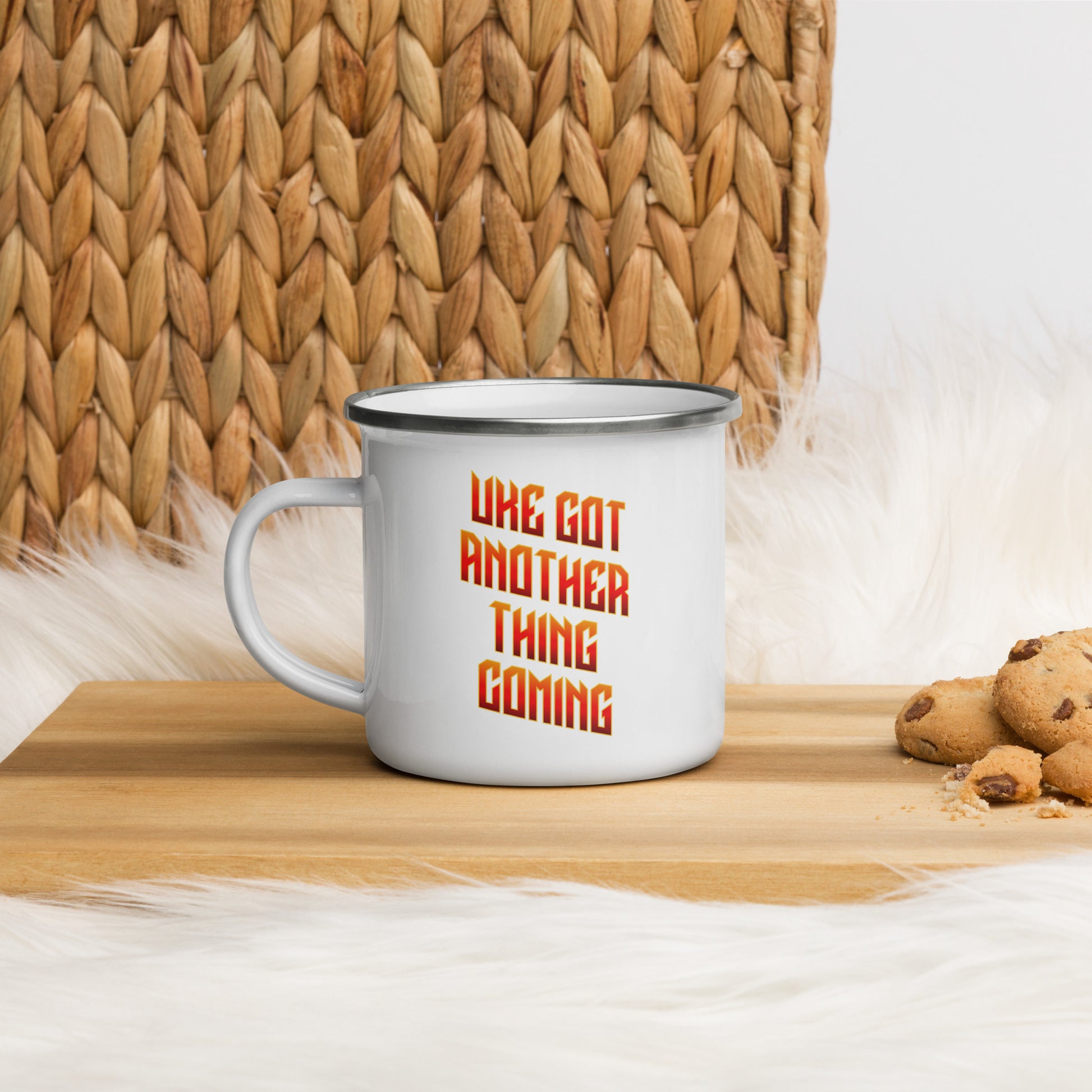 White enamel mug with ‘Uke Got Another Thing Coming' in orange and yellow slanted block letters printed on the side to the right of the mug handle.

