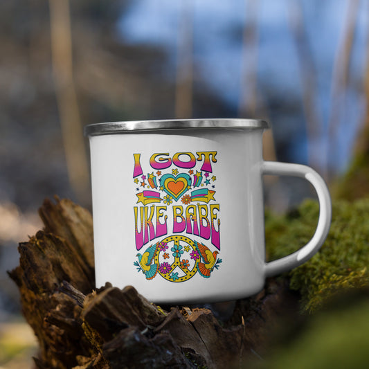 White enamel mug with 'I Got Uke Babe' and a pink, yellow, and blue peace sign graphic printed on the side to the left of the mug handle.