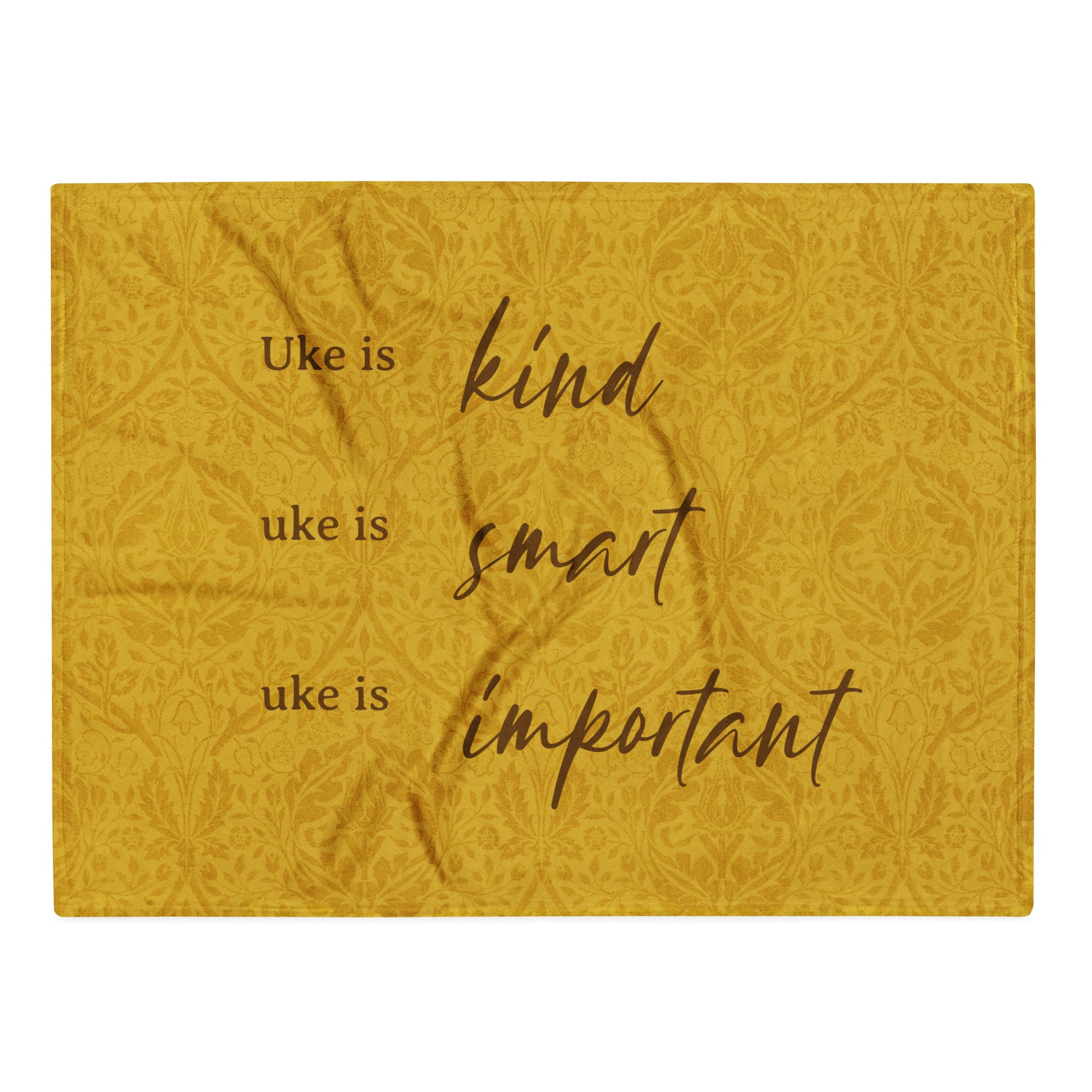 Microplush throw blanket with a mustard-colored, patterned background and 'Uke is kind, uke is smart, uke is important' printed on it.