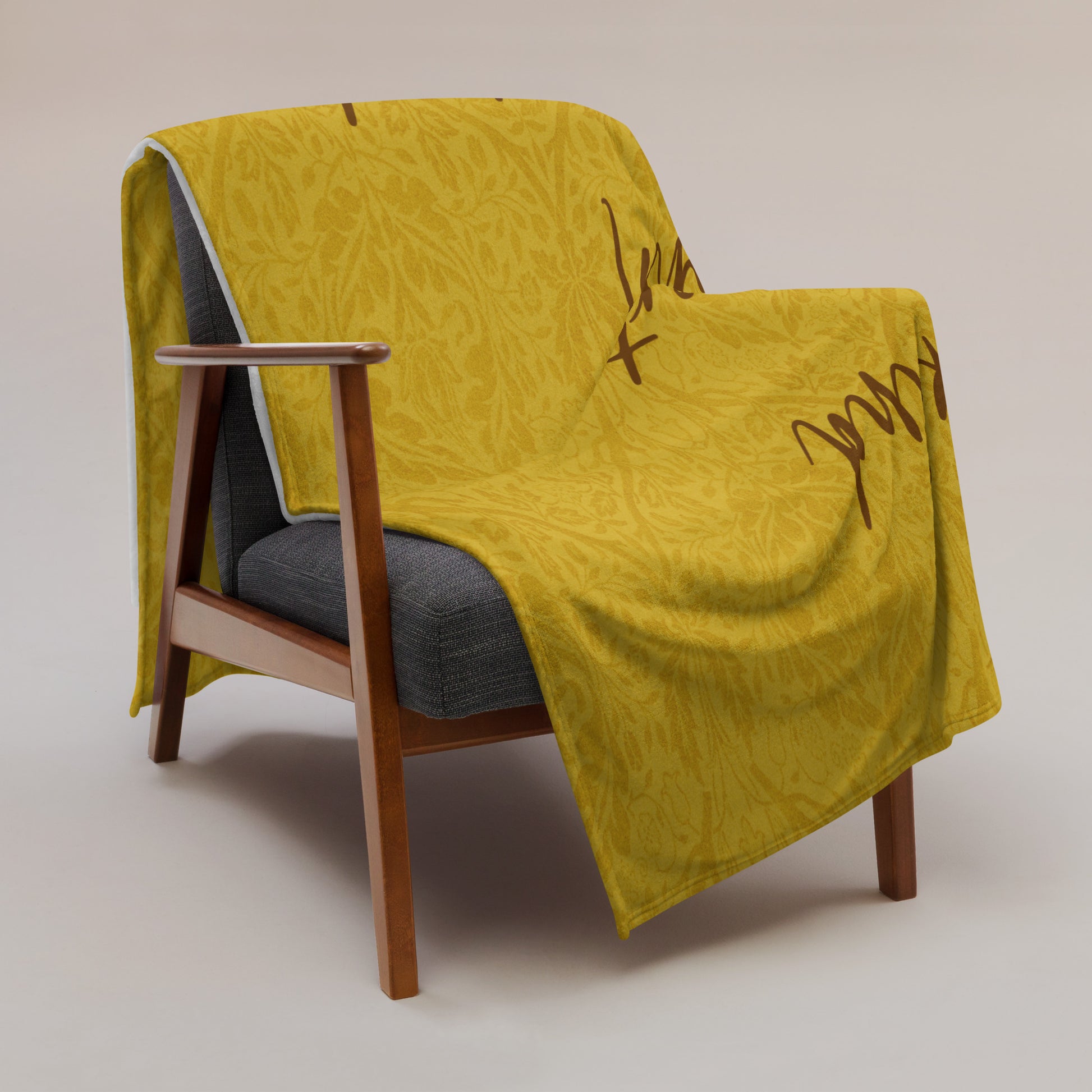 Microplush throw blanket with a mustard-colored, patterned background and 'Uke is kind, uke is smart, uke is important' printed on it, draped over a chair.