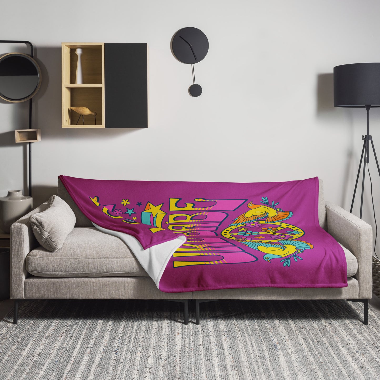 Microplush throw blanket with a dark pink background and a pink, blue, and yellow 'I Got Uke Babe' and peace sign graphic printed on it, draped over a sofa.