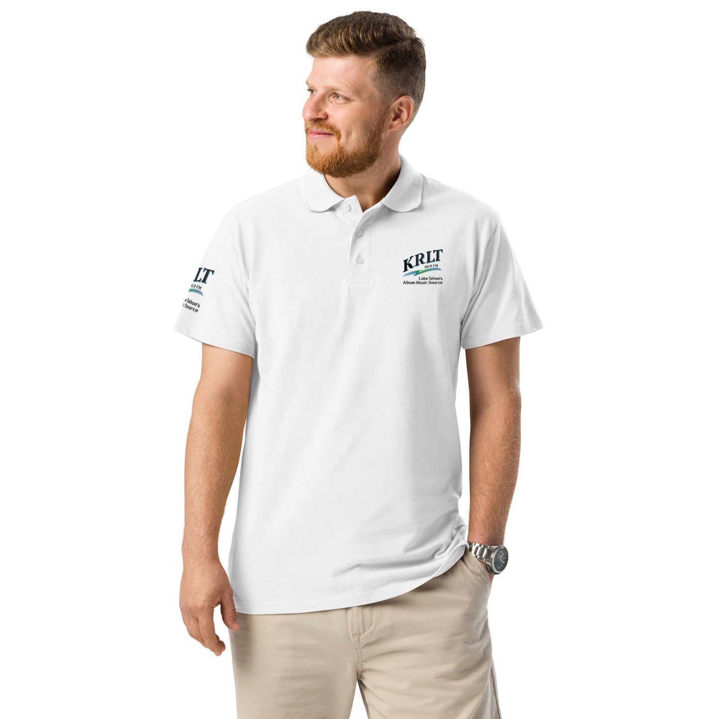Man wearing a white golf shirt with the KRLT logo in black, blue, and green, placed on the left upper-chest and right sleeve.