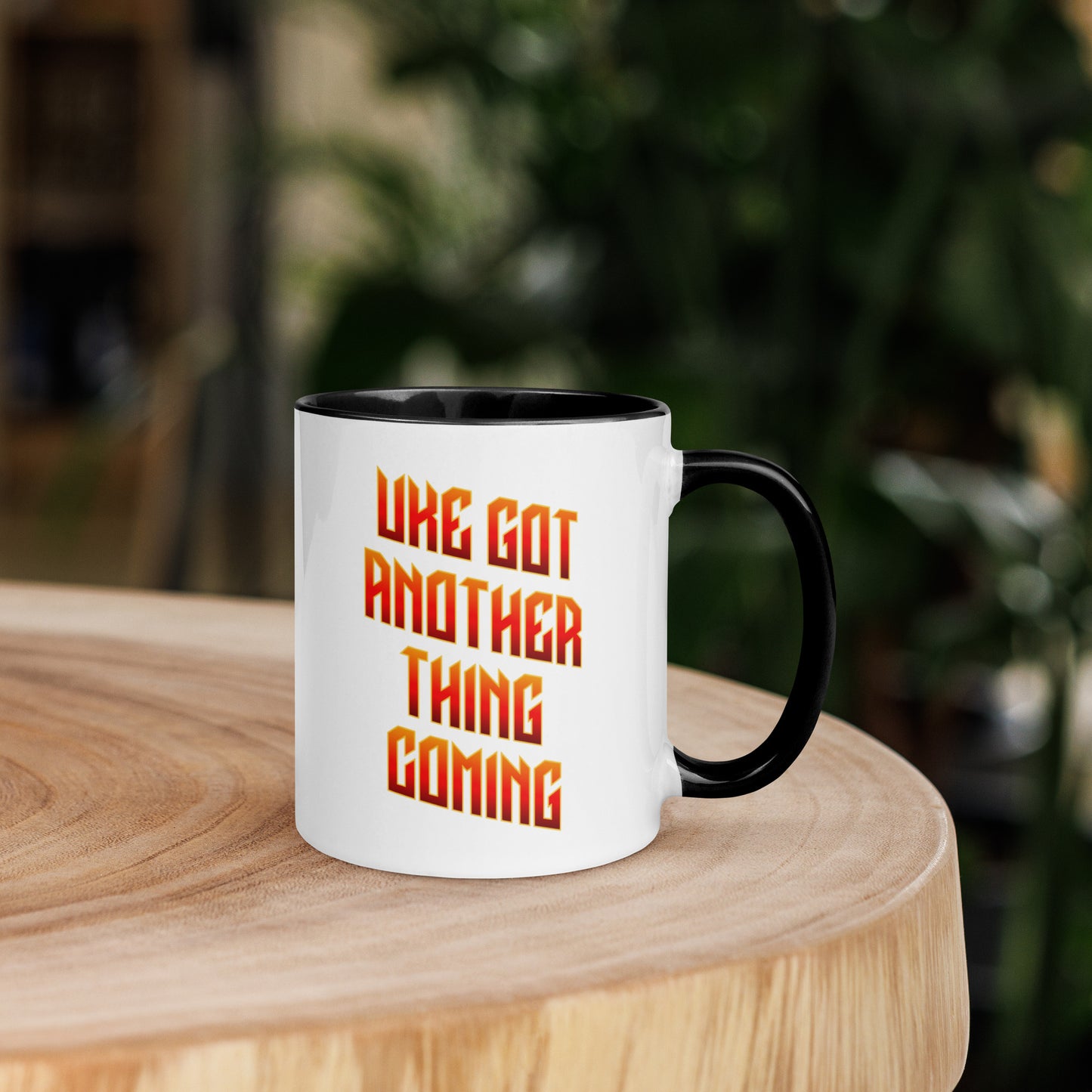 White mug with black handle and inside, with ‘Uke Got Another Thing Coming' in orange and yellow slanted block letters printed on the side to the left of the handle.