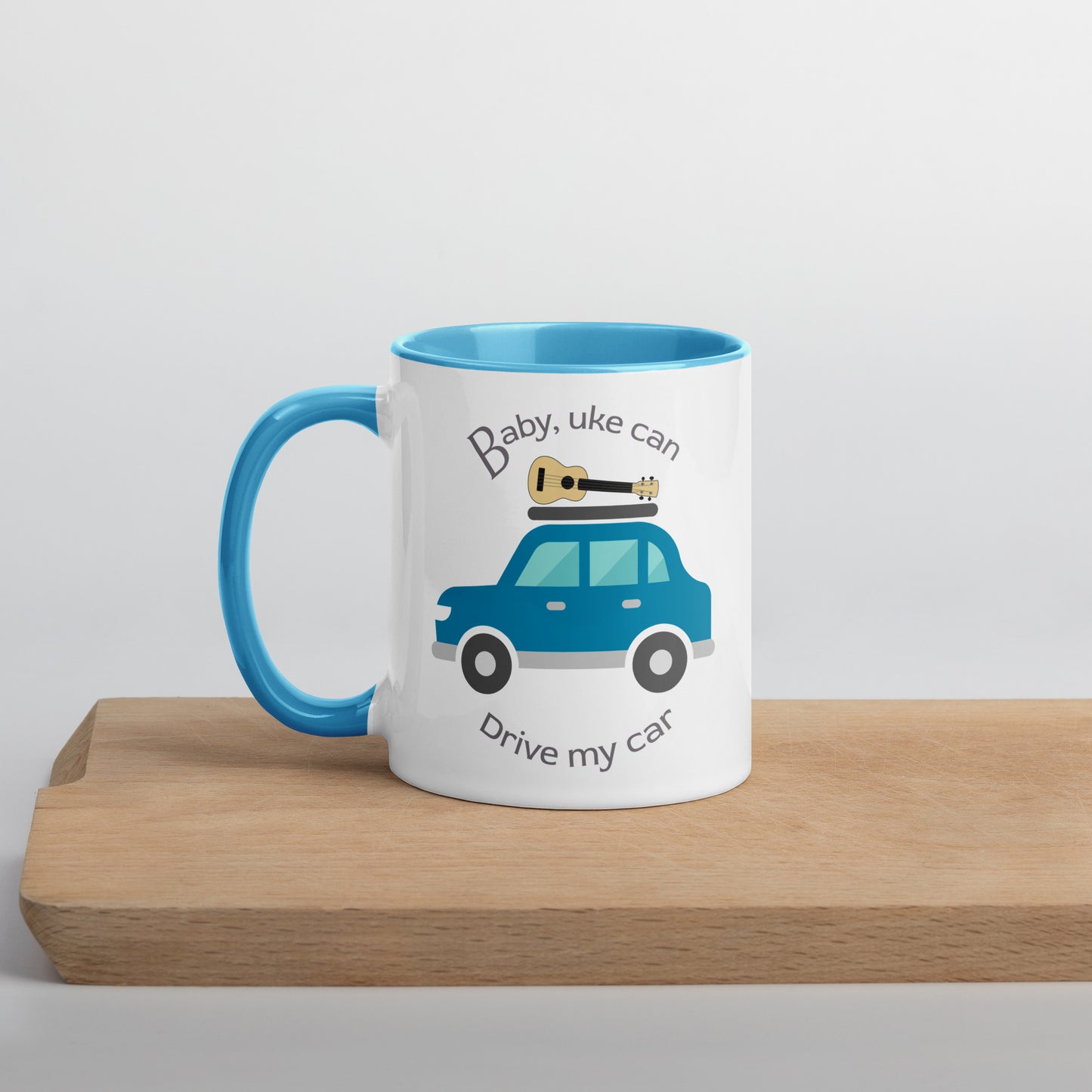 White mug with light blue handle and inside, with ‘Baby, uke can drive my car’ and a graphic of a car with a ukulele on the roof printed on the side to the right of the handle.