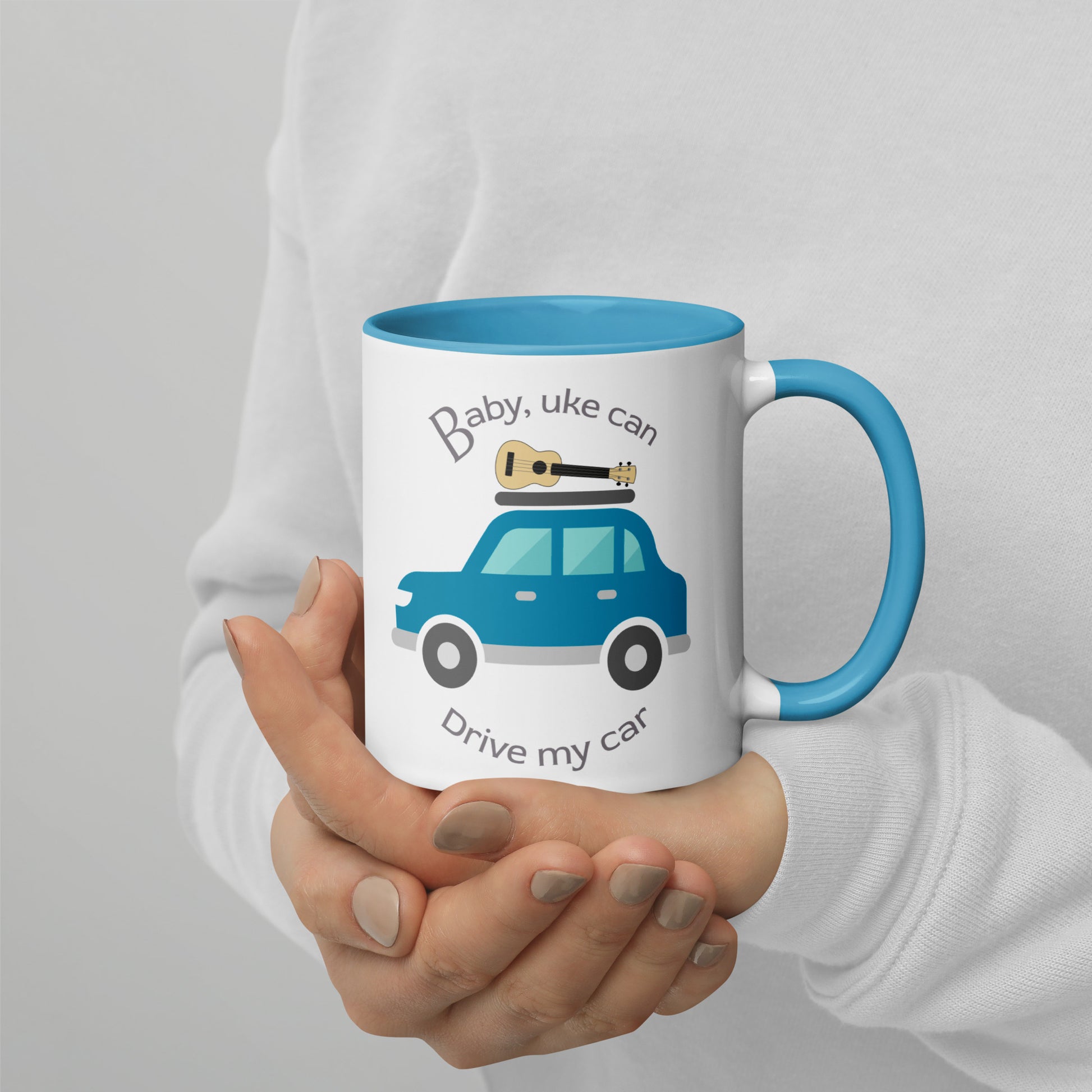 White mug with light blue handle and inside, with ‘Baby, uke can drive my car’ and a graphic of a car with a ukulele on the roof printed on the side to the left of the handle.