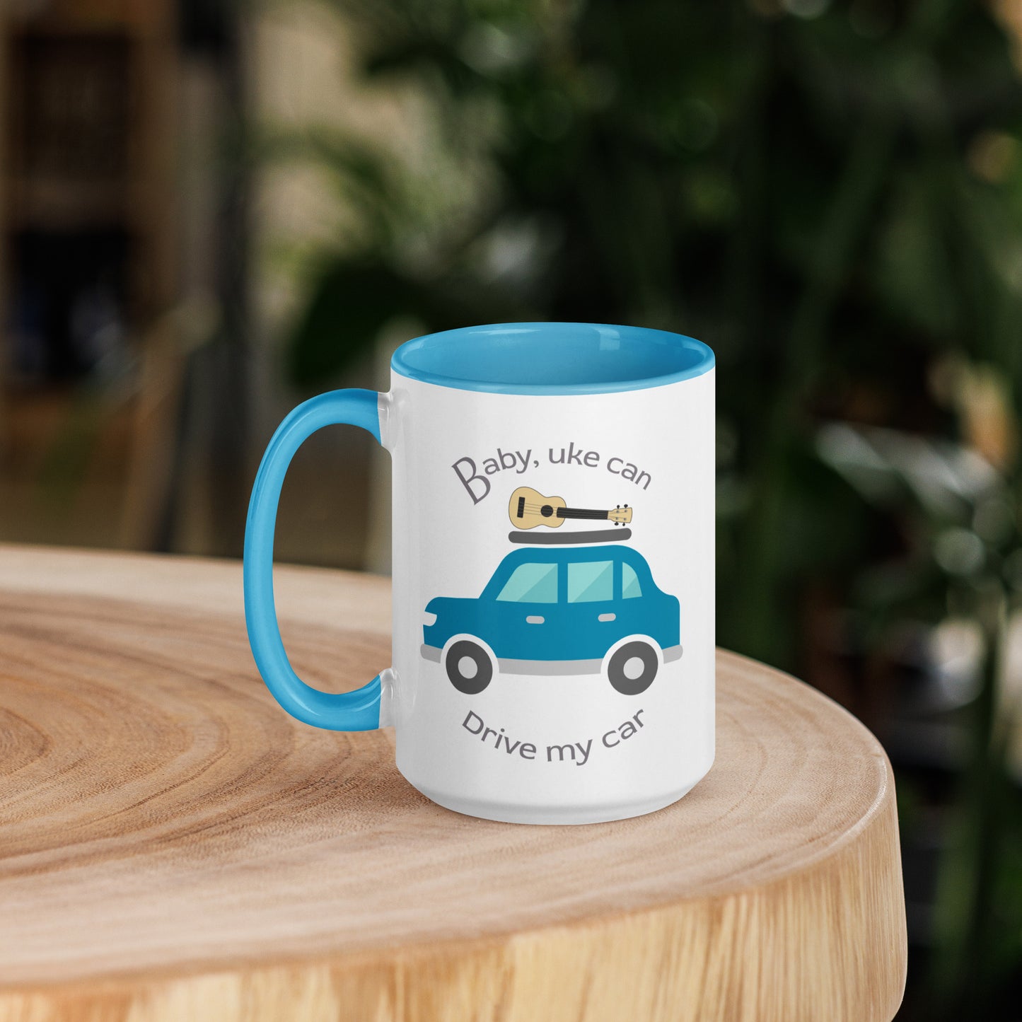15 ounce white mug with light blue handle and inside, with ‘Baby, uke can drive my car’ and a graphic of a car with a ukulele on the roof printed on the side to the right of the handle.