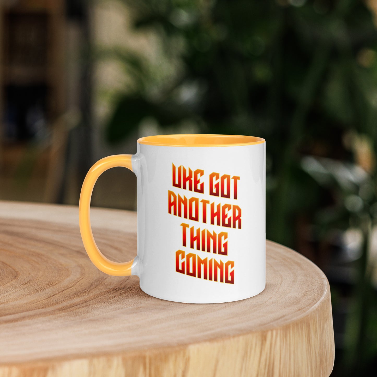 White mug with yellow handle and inside, with ‘Uke Got Another Thing Coming' in orange and yellow slanted block letters printed on the side to the right of the handle.