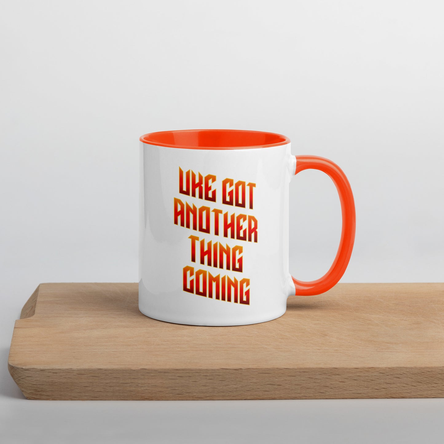 White mug with orange handle and inside, with ‘Uke Got Another Thing Coming' in orange and yellow slanted block letters printed on the side to the left of the handle.