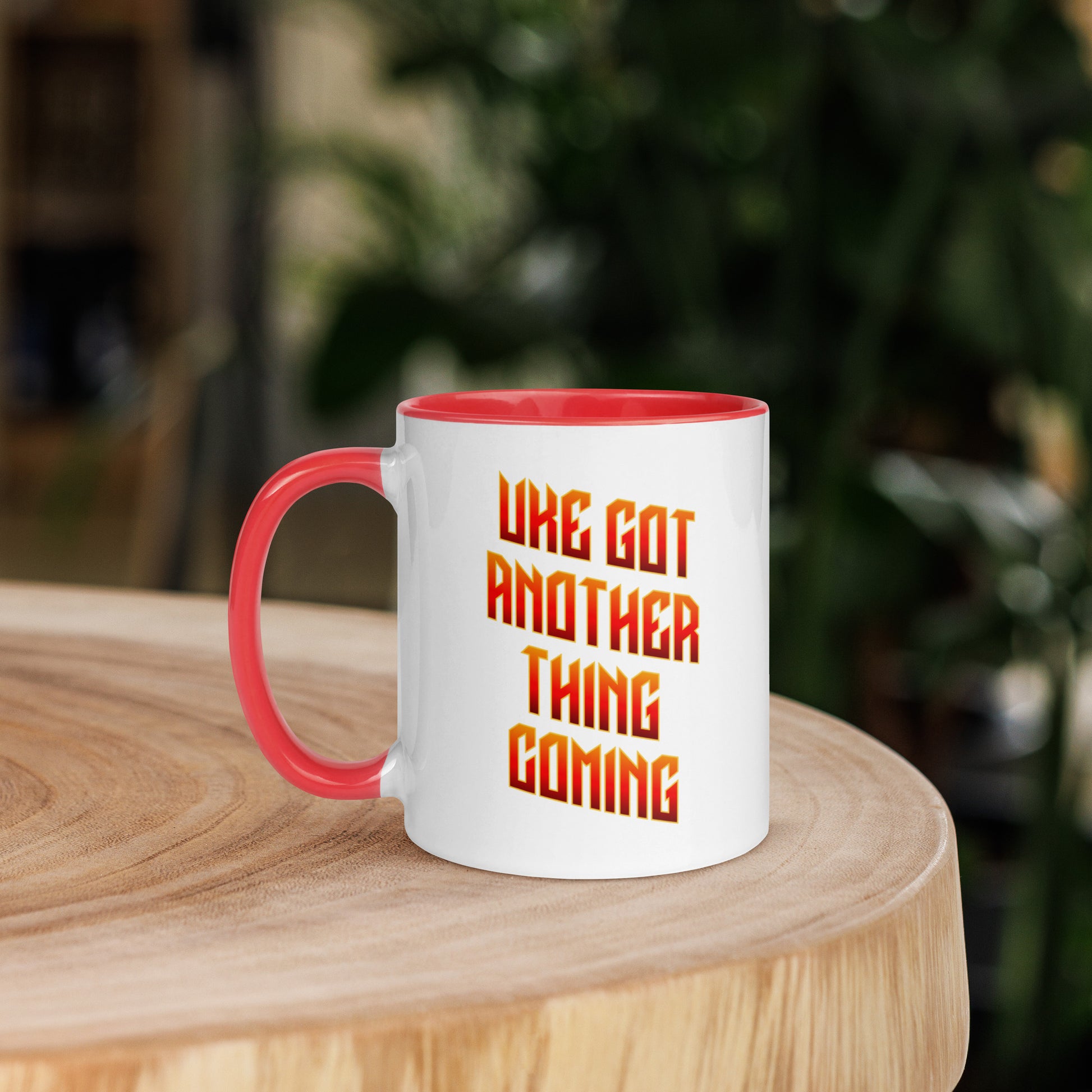 White mug with red handle and inside, with ‘Uke Got Another Thing Coming' in orange and yellow slanted block letters printed on the side to the right of the handle.
