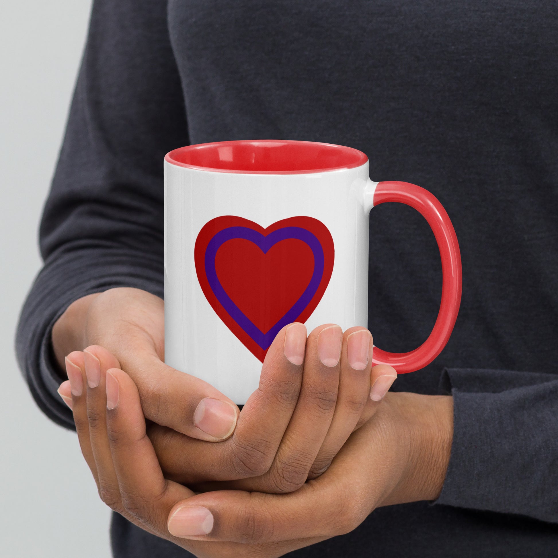 White mug with red handle and interior, with a red and purple heart printed on the side to the left of the handle.